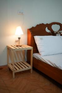 Una cama con una mesa con una lámpara. en Tom's House Motel & Motorbikes, en Làng Me