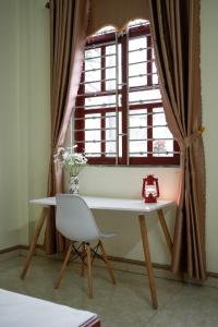 une table et une chaise devant une fenêtre dans l'établissement Tom's House Motel & Motorbikes, à Làng Me