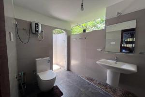 a bathroom with a white toilet and a sink at Sinharaja Rest in Deniyaya