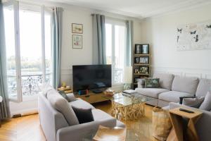 ein Wohnzimmer mit einem Sofa und einem TV in der Unterkunft EXIGEHOME-Appartement cosy avec vue sur la tour Eiffel in Saint-Cloud