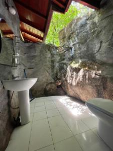 a bathroom with a sink and a rock wall at Sinharaja Rest in Deniyaya