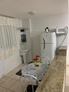 uma cozinha com uma mesa, um frigorífico e um lavatório em Belezas da Prainha em Arraial do Cabo