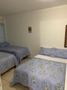 Duas camas num quarto com edredões azuis em Belezas da Prainha em Arraial do Cabo