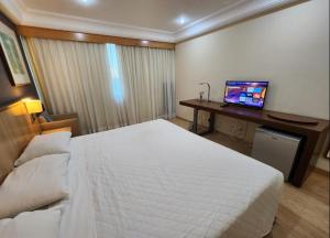 1 dormitorio con 1 cama y escritorio con ordenador en Flat Mediterrâneo.2, en Río de Janeiro
