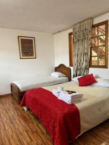 Cette chambre comprend 2 lits et une couverture rouge. dans l'établissement Hotel La Candelaria, à Ráquira