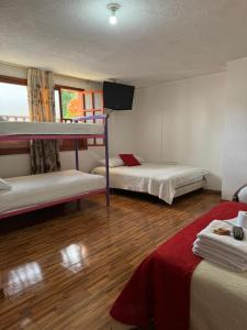 a room with two bunk beds and a flat screen tv at Hotel La Candelaria in Ráquira