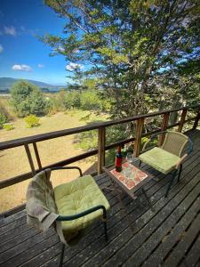 two chairs and a table on a deck with a drink at Suite con jacuzzi y bellas vistas in Lanalhue Lake