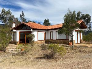 een klein wit huis met een rood dak bij Casa campestre Las Flores in Villa de Leyva