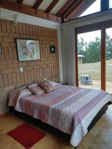 een slaapkamer met een bed met een bakstenen muur bij Casa campestre Las Flores in Villa de Leyva