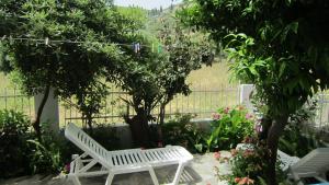 a white bench in a garden with trees and flowers at Sandalis Hotel in Pythagoreio