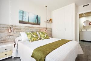um quarto com uma cama branca e um cobertor verde em Urban Sabadell Apartamentos em Sabadell