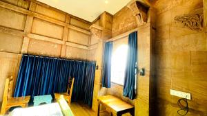 a room with a table and a window with blue curtains at Geel Heritage - A Restored Haveli in Jodhpur