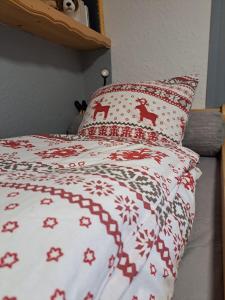 1 cama con edredón rojo y blanco y almohadas de ciervo en STUDIO 2 ALPES STYLE CHALET au PIED DE TELESIEGE DU DIABLE, en Les Deux Alpes