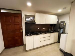 a kitchen with white cabinets and a brown door at Polanco Residences Tocagua Cartagena - Colombia in Cartagena de Indias