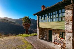 un edificio con un banco junto a una palmera en Casa BegoñaSituada en Sardedo Ribadesella en Linares