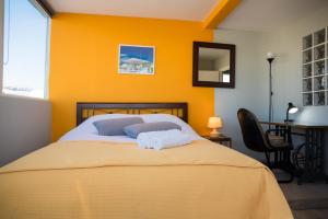 a yellow bedroom with a bed with two towels on it at 3C’s Athens South @Delta: SNFCC / Faliro Seaview Penthouse in Athens