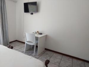 a white desk with a chair and a tv on a wall at New Lodge in Bloemfontein