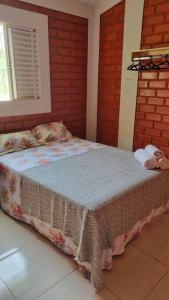 Bett in einem Zimmer mit Ziegelwand in der Unterkunft Riviera de Santa Cristina III, piscina e represa, tijolinho vermelho in Itaí