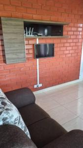 ein Wohnzimmer mit einem Sofa und einem TV an einer Backsteinwand in der Unterkunft Riviera de Santa Cristina III, piscina e represa, tijolinho vermelho in Itaí