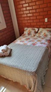 ein Bett mit einer Decke und Kissen darauf in der Unterkunft Riviera de Santa Cristina III, piscina e represa, tijolinho vermelho in Itaí