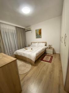Schlafzimmer mit einem weißen Bett und Holzboden in der Unterkunft Central Welcoming Apartment in Tirana in Tirana