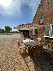 a table and chairs with an umbrella in front of a building at The Grooms Den in Fenny Compton