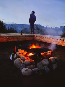 a man standing in front of a fire pit at Tinyhouse Pichi I - vida lenta en Patagonia Costa in Calbuco