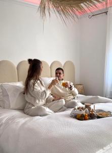 Ein Mann und eine Frau sitzen auf einem Bett und trinken Wein. in der Unterkunft CASA AMOR & SPA, suite jacuzzi & petit déjeuner in Montfort-sur-Argens