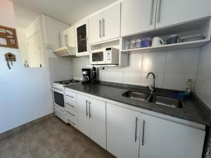 - une cuisine avec des placards blancs et un évier dans l'établissement Depto La Lucila, 3 ambientes, à La Lucila
