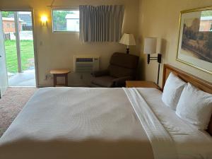 a hotel room with a large bed and a chair at Big Bend Traveler's Inn in Great Bend