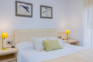 a bedroom with a white bed with two lamps at The Beach Apartment in El Puig