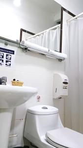 a white bathroom with a toilet and a sink at Di Costa Hotel in Piura