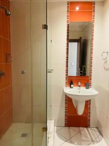 uma casa de banho com um lavatório e uma cabina de duche em vidro. em Marble nights em Joanesburgo