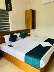 a bedroom with a large white bed with blue pillows at Regalia Wayanad in Kalpetta