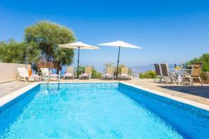 a swimming pool with chairs and umbrellas and a table at Villa Panorama Tessera in Droushia