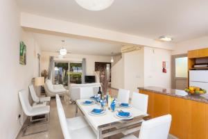 een keuken en eetkamer met een witte tafel en stoelen bij Villa Panorama Tessera in Droushia