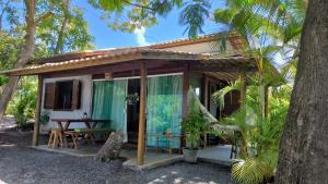 a small house with a table and a tree at Chalé "Oasis" in Praia do Forte