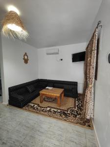 a living room with a black couch and a table at Dar Barka in Kebili