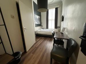 Kleines Zimmer mit einem Schreibtisch und einem Bett. in der Unterkunft Hotel Hortus in Amsterdam