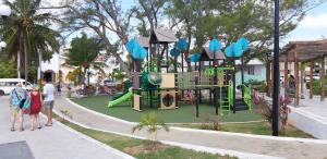 une aire de jeux dans un parc avec des personnes debout sur un trottoir dans l'établissement Corte de Los Angeles, à Puerto Morelos