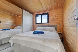 two beds in a room with wooden walls at Choller Farm Lodge - Private Hot Tub in Slindon