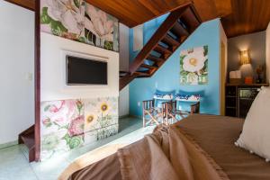 a bedroom with a bed and a tv on a wall at Vila Charme in Jericoacoara