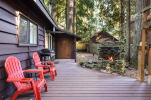 two red chairs sitting on a wooden porch with a fireplace at Mystic Mountain in Rhododendron
