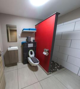 een badkamer met een toilet en een rode deur bij l'hôt'antique in Vielsalm