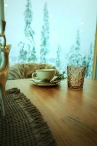 a cup and a plate on a wooden table at Villa Auroras Kettu in Syöte