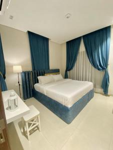 a bedroom with a large bed with blue curtains at The Beach House in Muscat