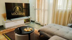 a living room with a couch and a flat screen tv at LOCABISS Appartement VIP in Rufisque