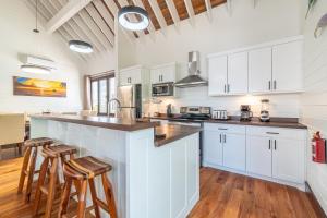 a kitchen with white cabinets and bar stools at Backroads Sunset + The PoolClub at Mahogany Bay in San Pedro