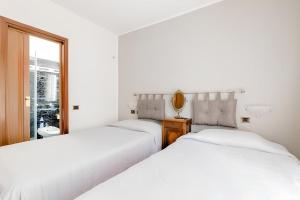 2 bedden in een witte kamer met een raam bij Garden House Fiera Milano in Pero