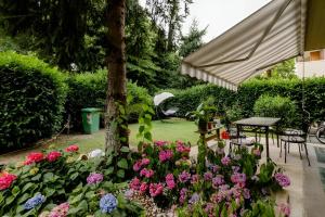 a garden with pink and purple flowers and an umbrella at Garden House Fiera Milano in Pero